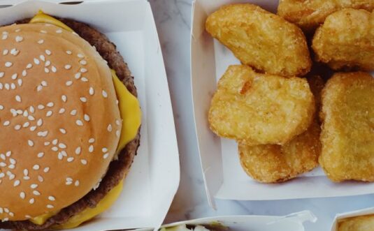 Closeup of delicious junk food consisting of burgers with nuggets and french fries placed on marble table