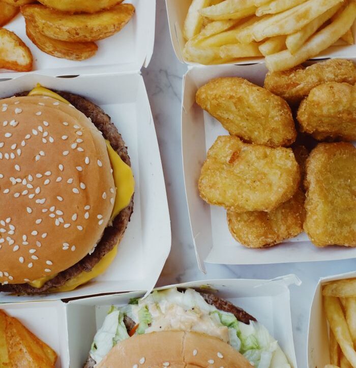 Closeup of delicious junk food consisting of burgers with nuggets and french fries placed on marble table
